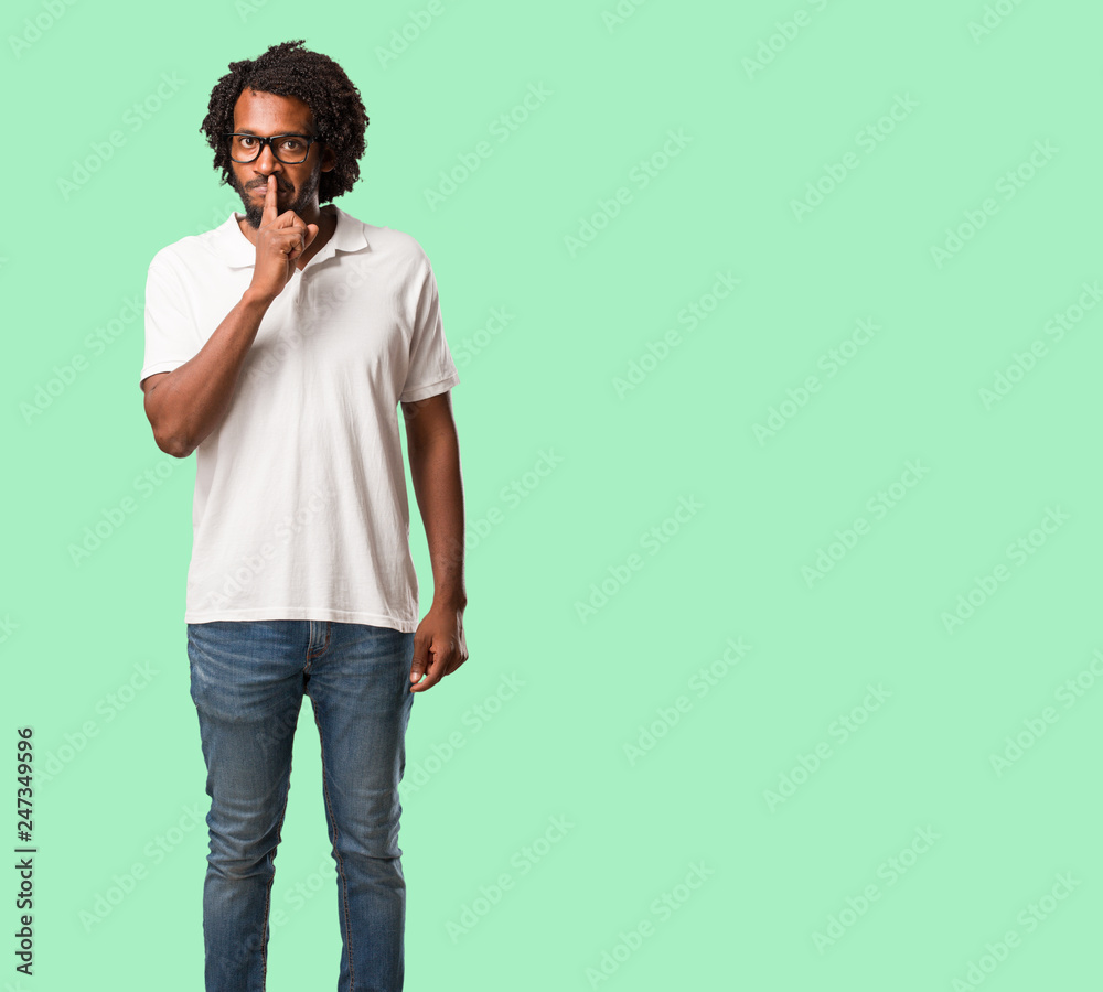 Handsome african american keeping a secret or asking for silence, serious face, obedience concept Handsome african american keeping a secret or asking for silence, serious face, obedience concept