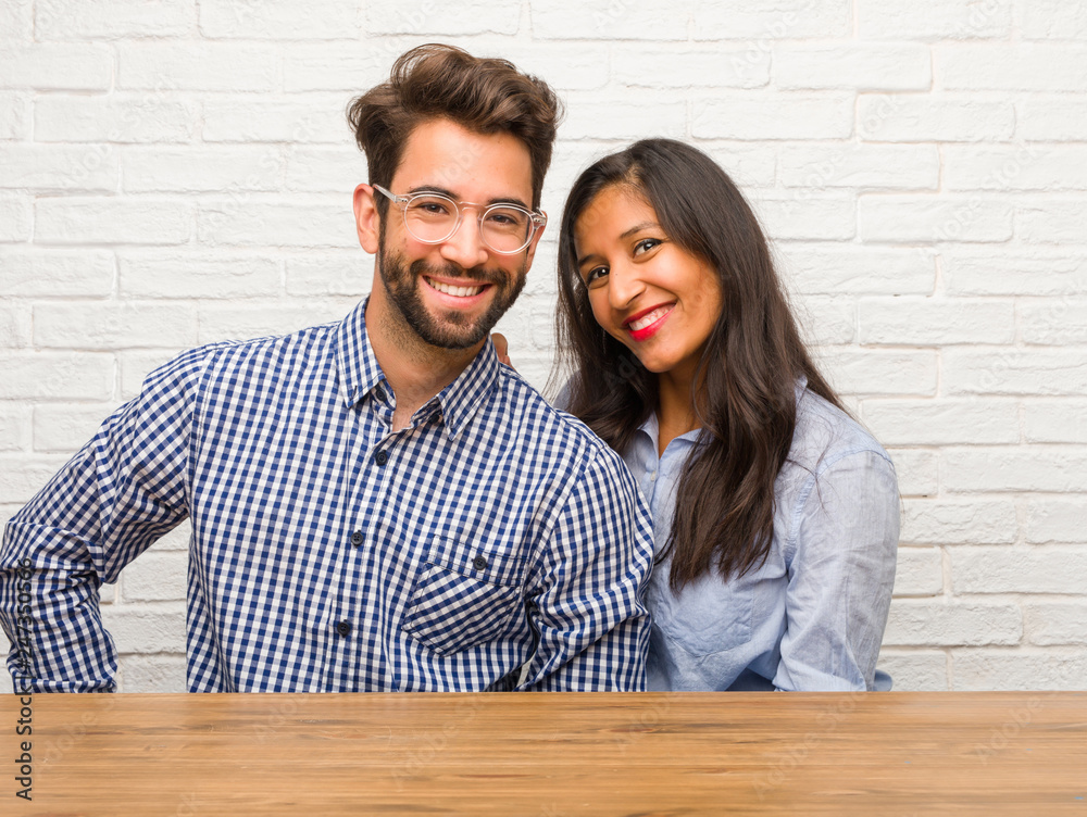 Young indian woman and caucasian man couple with hands on hips, standing, relaxed and smiling, very positive and cheerful Young indian woman and caucasian man couple with hands on hips, standing, relaxed and smiling, very positive and cheerful