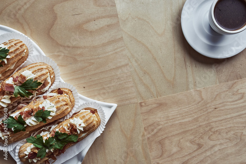 Tasty eclairs on wooden table, close up