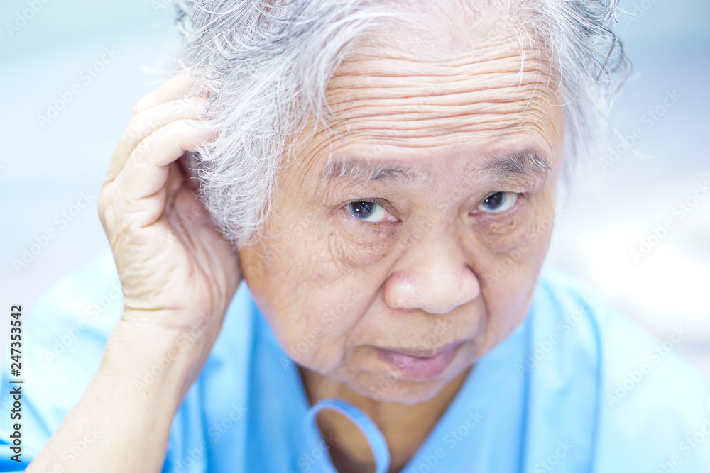 Asian senior or elderly old lady woman patient try to listen ear, hard of hearing, deafness while lying on bed in nursing hospital ward : healthy strong medical concept Asian senior or elderly old lady woman patient try to listen ear, hard of hearing, deafness while lying on bed in nursing hospital ward : healthy strong medical concept