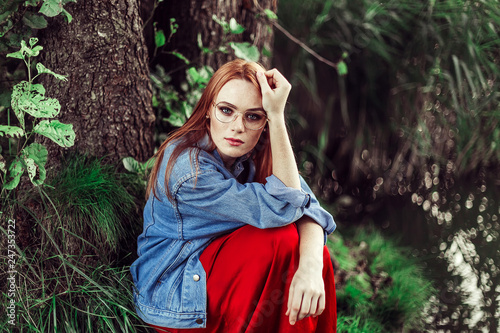 Portrait of young tender redhead young girl with healthy freckled skin wearing white top looking at camera with serious or pensive expression. Caucasian woman model with ginger hair posing outdoors