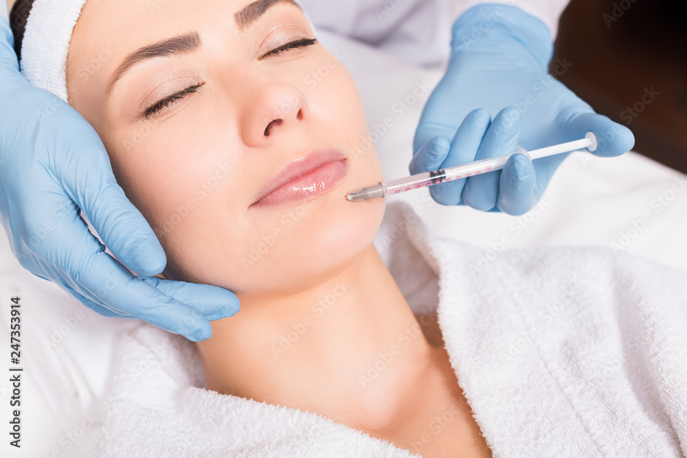 cropped view of beautician making injection face attractive woman at beauty salon cropped view of beautician making injection face attractive woman at beauty salon