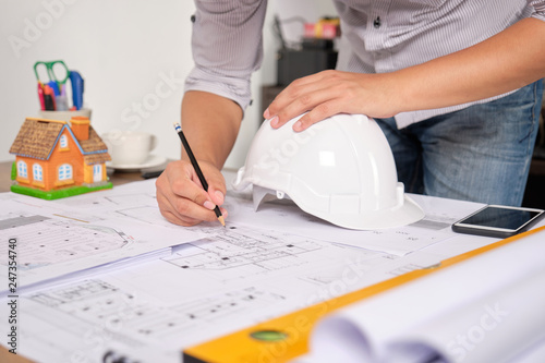 Architect is drawing construction plans on Blueprint paper with pencil. Selective Focus.