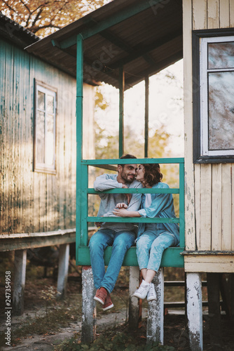 Cute romantic couple sitting on porch of wooden cabin.