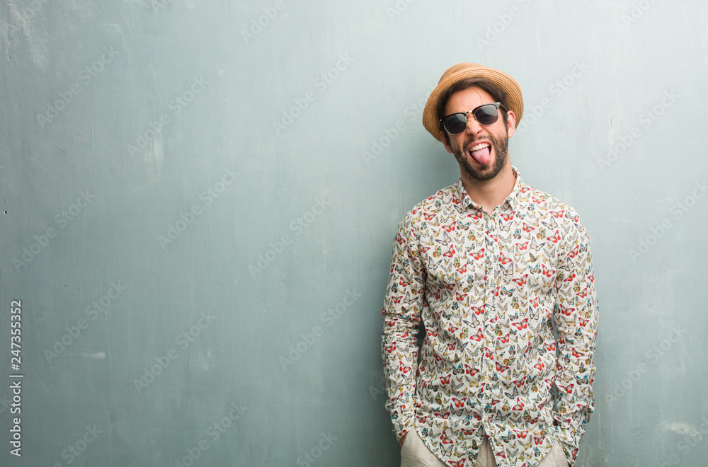 Young traveler man wearing a colorful shirt expression of confidence and emotion, fun and friendly, showing tongue as a sign of play or fun Young traveler man wearing a colorful shirt expression of confidence and emotion, fun and friendly, showing tongue as a sign of play or fun