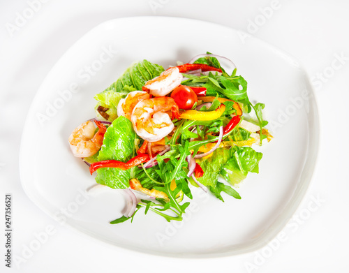 Delicious salad with shrimp, tomatoes and greenery on white