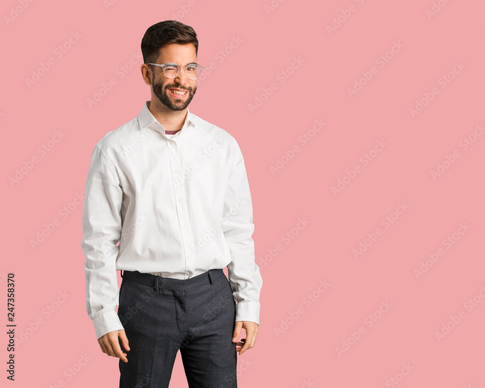 Fototapeta premium Young handsome business man winking, funny, friendly and carefree gesture