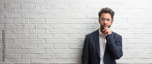 Φωτογραφία Young friendly business man doubting and confused, thinking of an idea or worrie