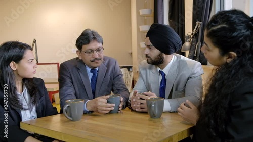 Serious discussion with business colleagues as they discuss important matters over coffee in a break out area 