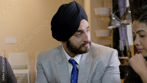 Pan left to right and back as a livid and angry turbaned Sikh boss is seeking answers and berating his clueless and incapable team, who look lost and speechless  photo