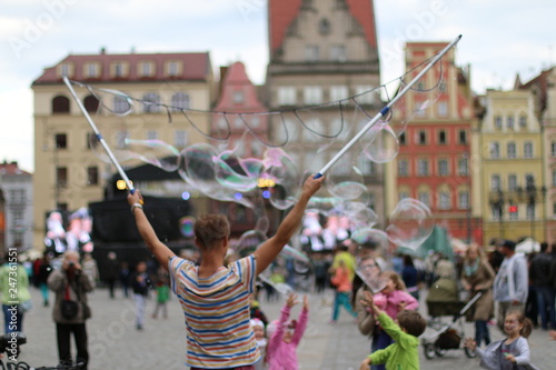 Man blowing beautiful, soap bubbles. Warm, pleasant, spring day. Family atmosphere in the outdoors. Active rest, weekend in the city. Relaxing people. Great fun outside. Variety of colors. Freedom.