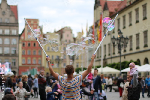 Man blowing beautiful, soap bubbles. Warm, pleasant, spring day. Family atmosphere in the outdoors. Active rest, weekend in the city. Relaxing people. Great fun outside. Variety of colors. Freedom.