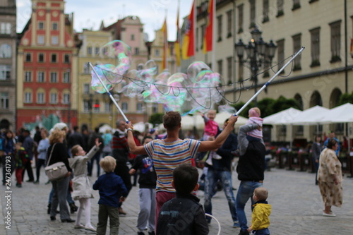Man blowing beautiful, soap bubbles. Warm, pleasant, spring day. Family atmosphere in the outdoors. Active rest, weekend in the city. Relaxing people. Great fun outside. Variety of colors. Freedom.