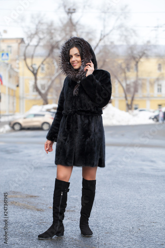 Young beautiful brunette woman in fur coat posing on winter park © Andrey_Arkusha