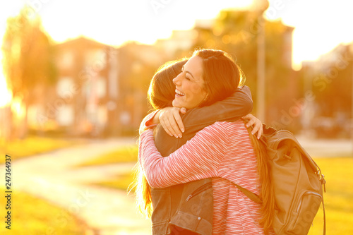 Happy friends meeting and hugging in a park at sunset photo
