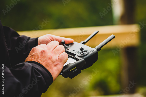 Hand holding drone quadcopter UAV remote control console controls.