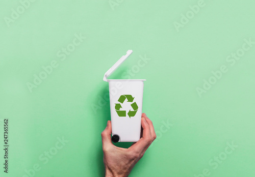 Hand holding recycling rubbish bin against a green background photo