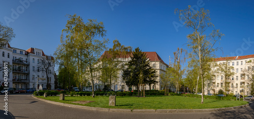 Der kreisrunde Renée-Sintenis-Platz in Berlin-Friedenau ist heute ein Gartendenkmal. Im Hintergrund das ebenfalls denkmalgeschützte Friedenauer Postamt - Panorama aus 6 Einzelbildern