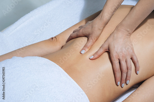 Hands of unrecognisable woman masseur doing back massage at salon. photo