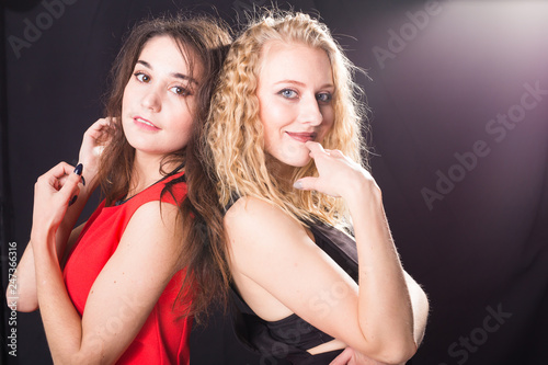 Friendship and girl power concept - Young happy women friends standing over dark background