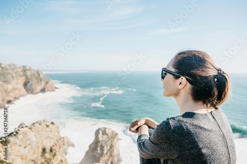 The girl at the top of the cliff in solitude admires the beautiful view of the Atlantic Ocean.