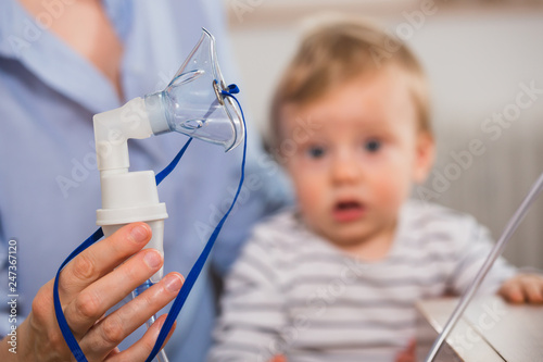 close up of nebuliser inhalation mask with baby boy in blurred background