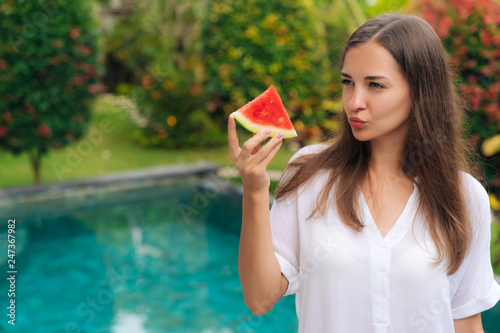 Portrait thoughtful girl with long hair holding slice of watermelon in her hand