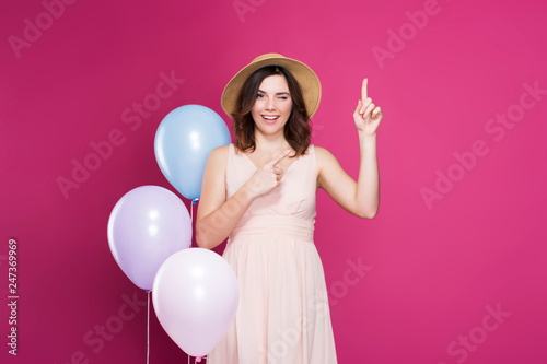 girl in a dress and a straw hat on a pink background 