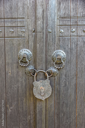 an old wooden door locked with a big vintage padlock. True village style