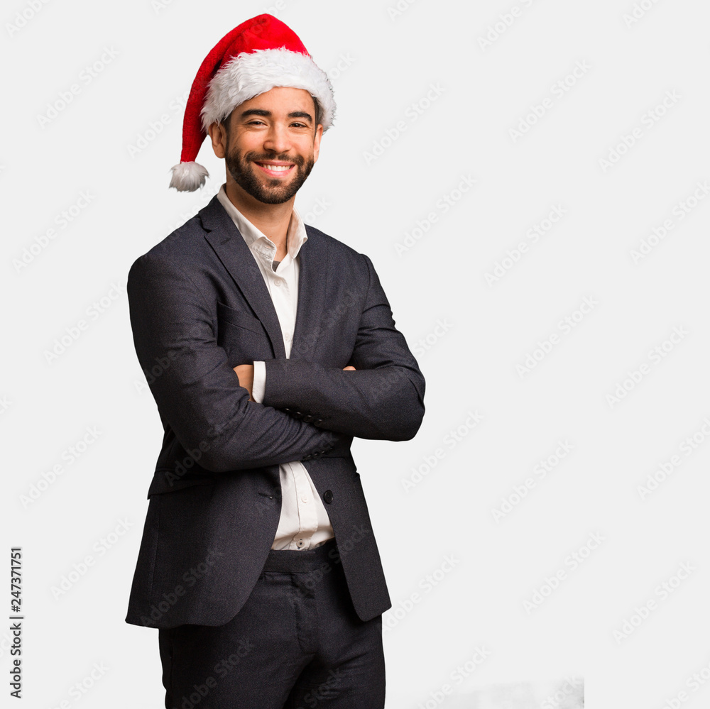 Young business man wearing santa hat crossing arms, smiling and relaxed Young business man wearing santa hat crossing arms, smiling and relaxed