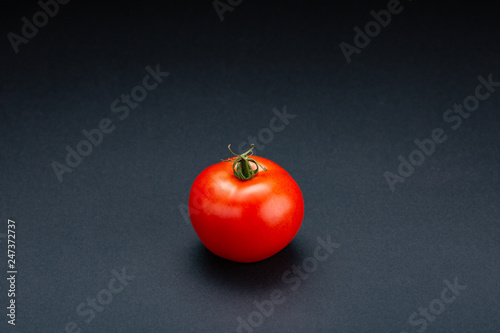 Tomato on a black background with realistic reflection