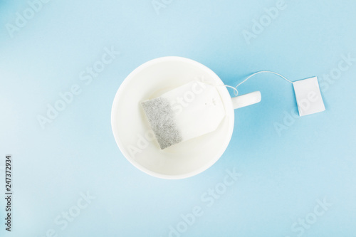 Cup of tea and tea bags on blue background. Top view. Food background