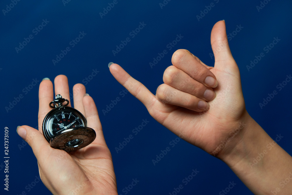 Fototapeta premium pocket watch on a chain in hand, shaka, blue background