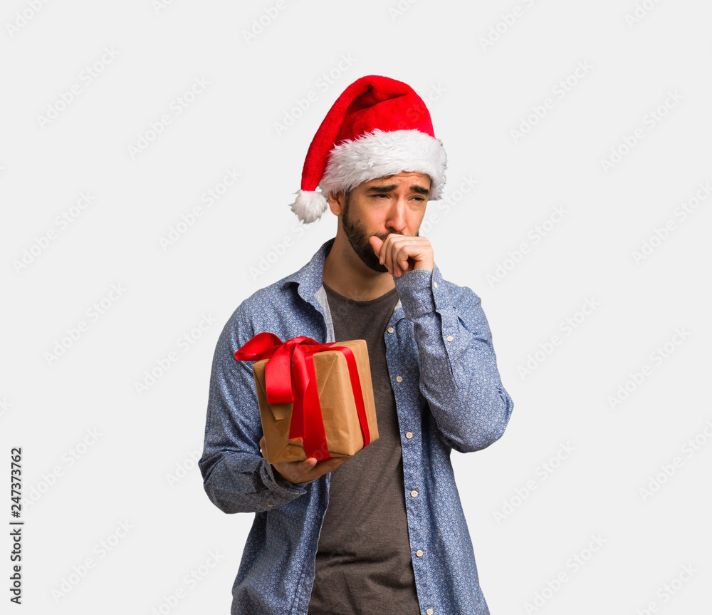 Young man wearing santa hat coughing, sick due a virus or infection Young man wearing santa hat coughing, sick due a virus or infection