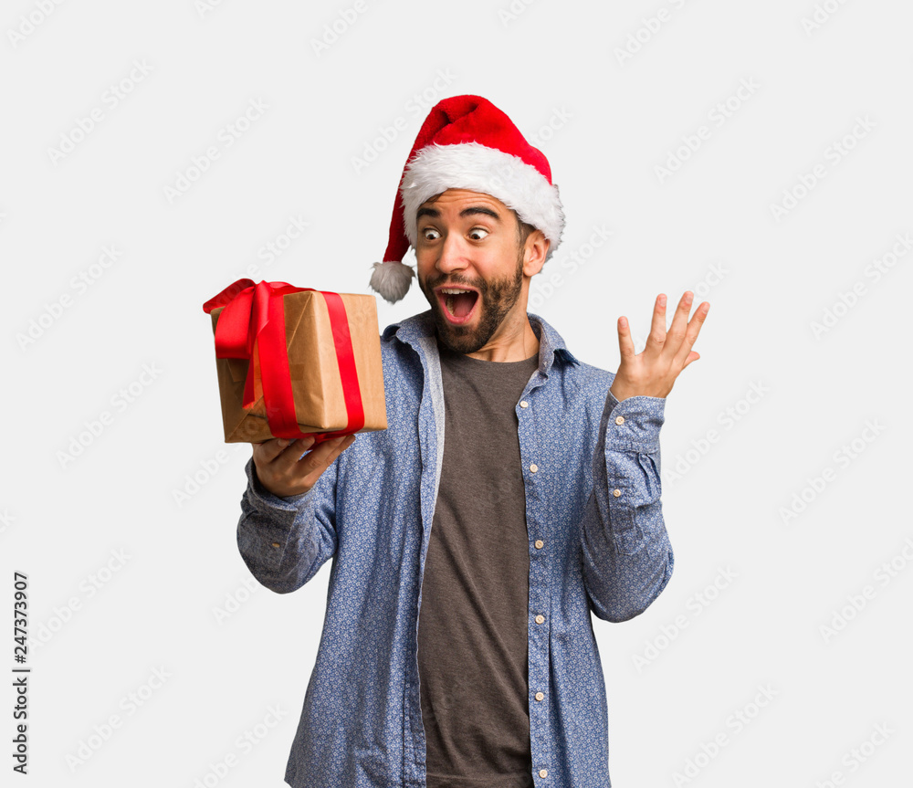 Young man wearing santa hat celebrating a victory or success Young man wearing santa hat celebrating a victory or success