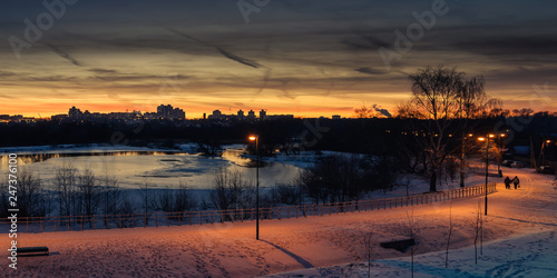 winter evening cityscape. view of the residential area across the river in the background of the sunset