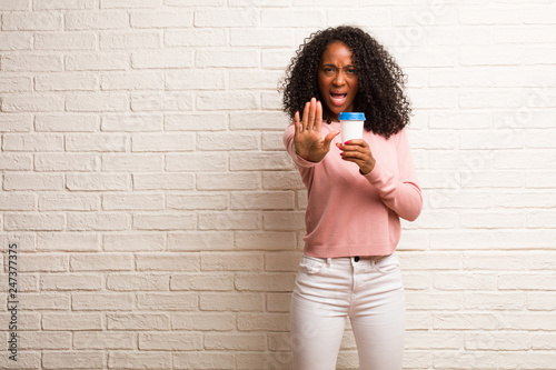 Young black woman serious and determined, putting hand in front, stop gesture, deny concept