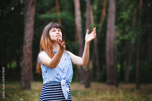 Beautiful young woman praying outdoors with hands up, religion and christianity concept