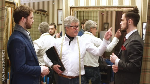 Two handsome and successful businessman trying on a custom made stylish suit at tailors shop. Dressmaking and Tailoring establishment concept photo