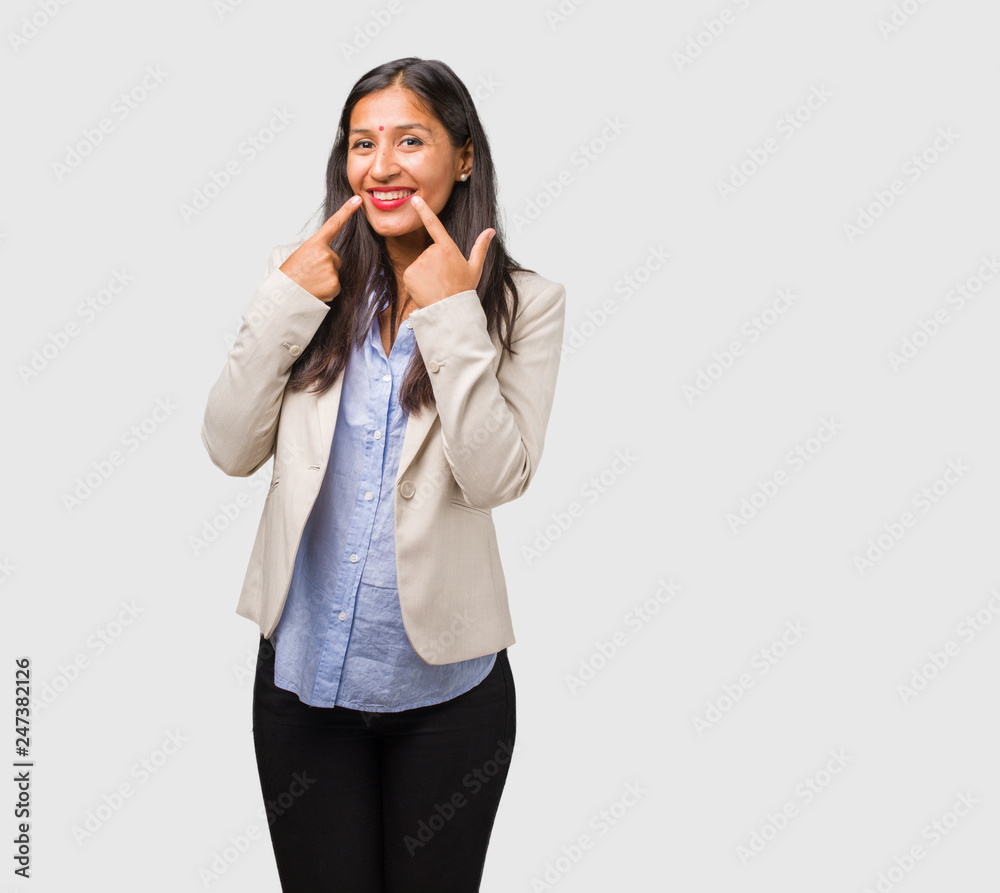 Young business indian woman smiles, pointing mouth, concept of perfect teeth, white teeth, has a cheerful and jovial attitude Young business indian woman smiles, pointing mouth, concept of perfect teeth, white teeth, has a cheerful and jovial attitude