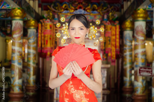 happy Chinese new year. Asian girl with gesture of congratulation and holding red envelope on Chinese temple background. © kowit1982
