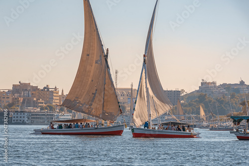 12.11.2018 Aswan, Egypt, A boat felucca sailing along a river of nilies on a sunny day against a city background photo