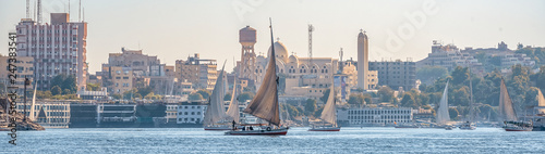 12.11.2018 Aswan, Egypt, A boat felucca sailing along a river of nilies on a sunny day against a city background photo