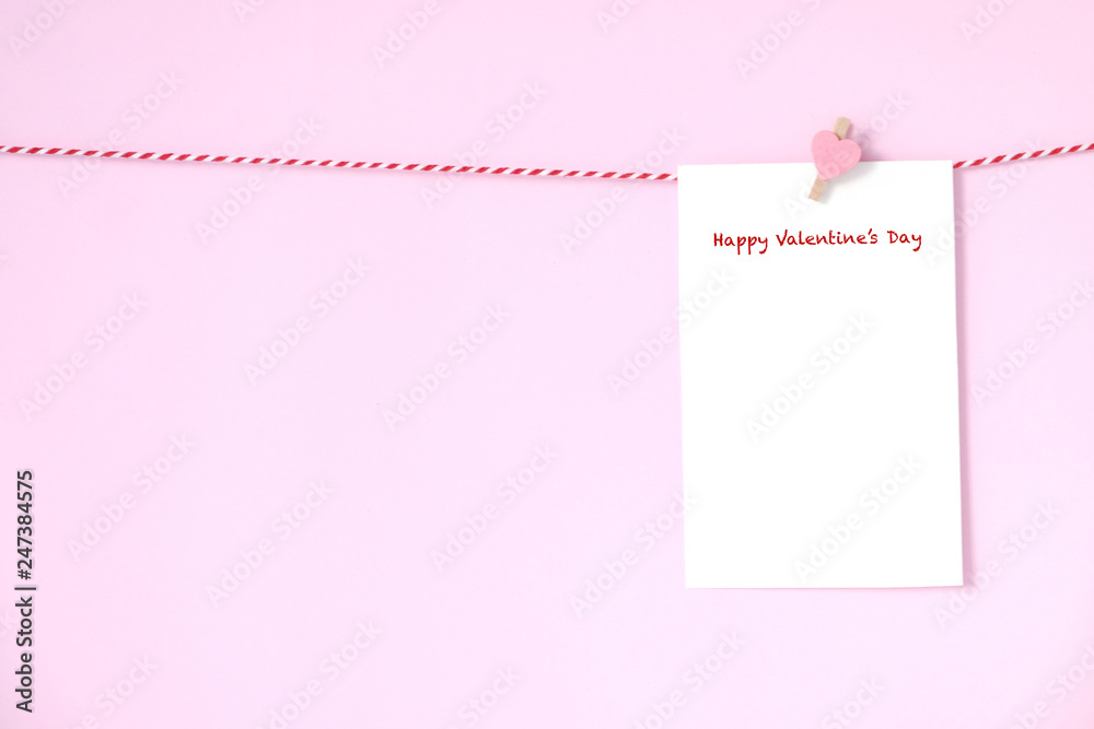 Happy valentine’s day on blank white paper notepad hanging on pink background, with copy space for text