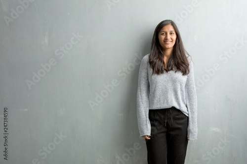 Young indian woman against a grunge wall cheerful and with a big smile, confident, friendly and sincere, expressing positivity and success