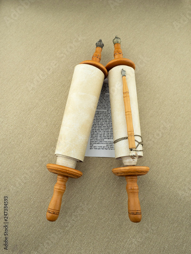 A scroll of the Torah on wooden bonds, a pointer, a rough canvas.