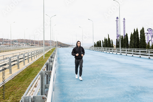 Nice tall young gay runner runs through a scenic nature during a morning jog. Concept of weight loss and cardio. Place for your advertising content