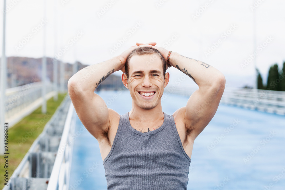 Close-up portrait of a strong positive guy trainer posing during a morning workout on a summer morning. Concept of good physical condition and excellent health. Place for text Close-up portrait of a strong positive guy trainer posing during a morning workout on a summer morning. Concept of good physical condition and excellent health. Place for text