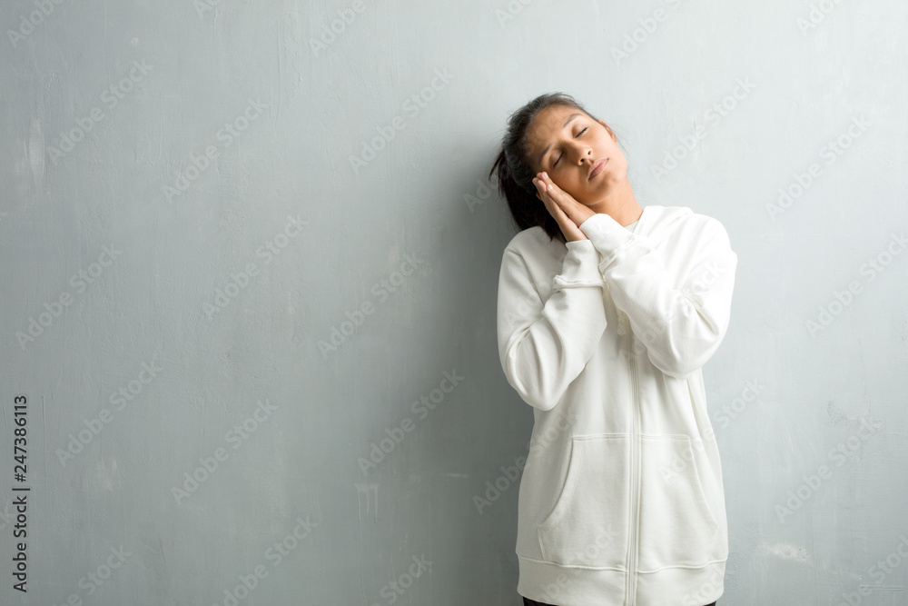 Young sporty indian woman against a gym wall tired and very sleepy, looking comfortable and relaxed, sleep gesture Young sporty indian woman against a gym wall tired and very sleepy, looking comfortable and relaxed, sleep gesture
