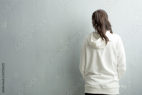 Tableau sur toile Young sporty indian woman against a gym wall showing back, posing and waiting, l